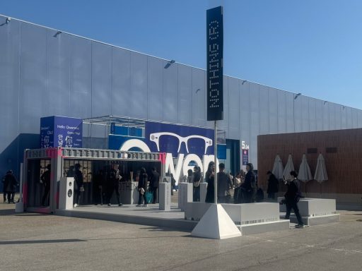 Exterior de un edificio con personas haciendo cola y carteles publicitarios.